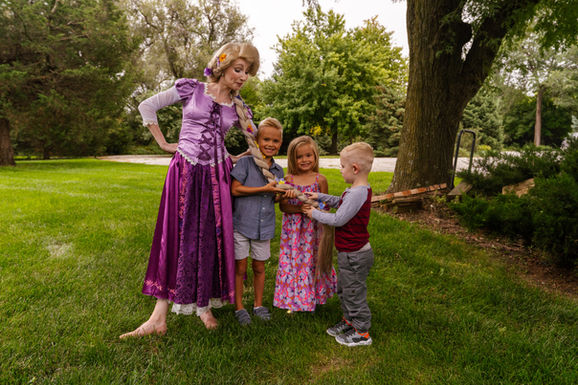 Rapunzel outdoors with three children holding her long braid