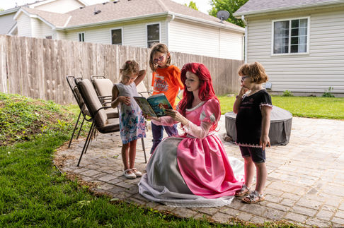 Little Mermaid reading a book to children outdoors